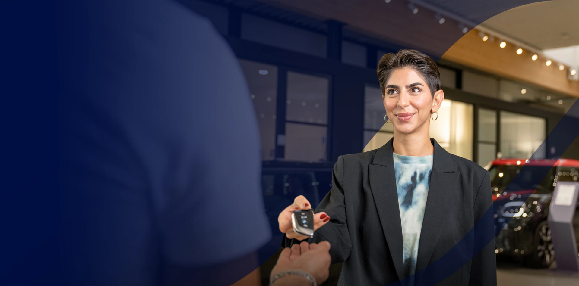 Eine junge Dame überreicht einen BMW Fahrzeugschlüssel.