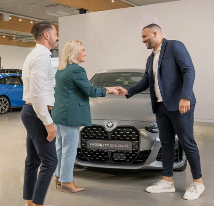 Ein Verkaufsberater begrüßt seine Kundin zur Fahrzeugabholung.