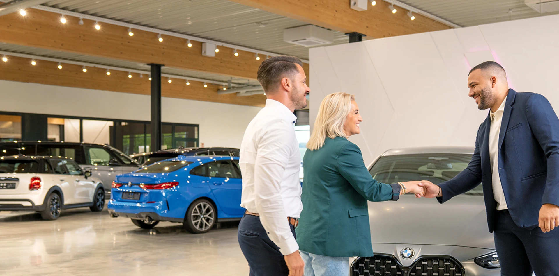 Ein Verkaufsberater begrüßt seine Kundin zur Fahrzeugabholung.